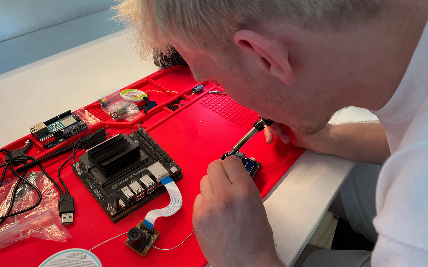 Jeremias soldering prototype electronics beside an NVIDIA Jetson Orin Nano and camera module